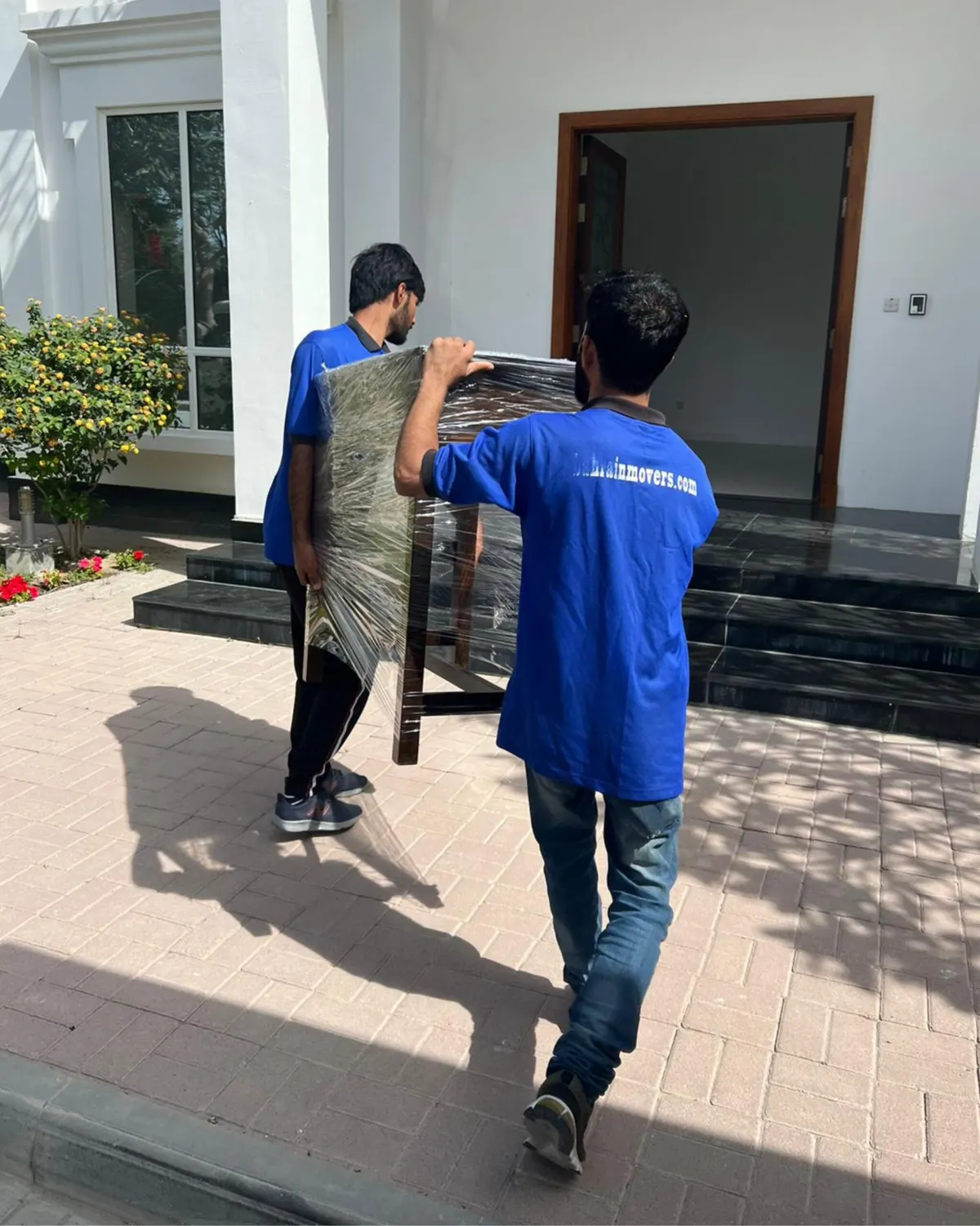 Crew carrying a wrapped item into a villa