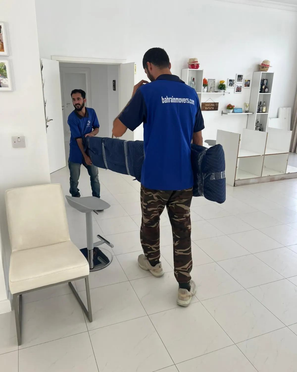Two crew members carrying a wrapped piece through a living room